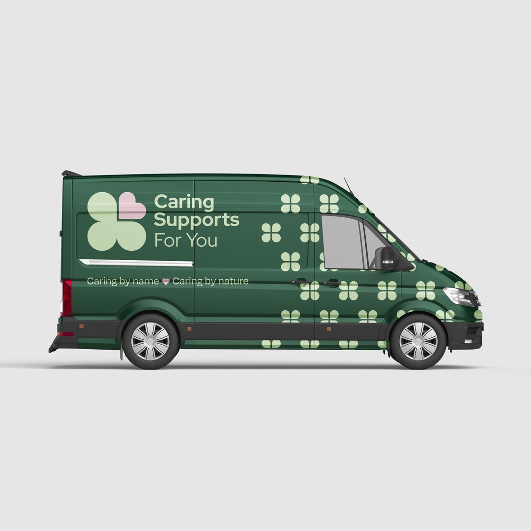 Dark green van wrapped with the Caring Supports For You logo and a clover pattern